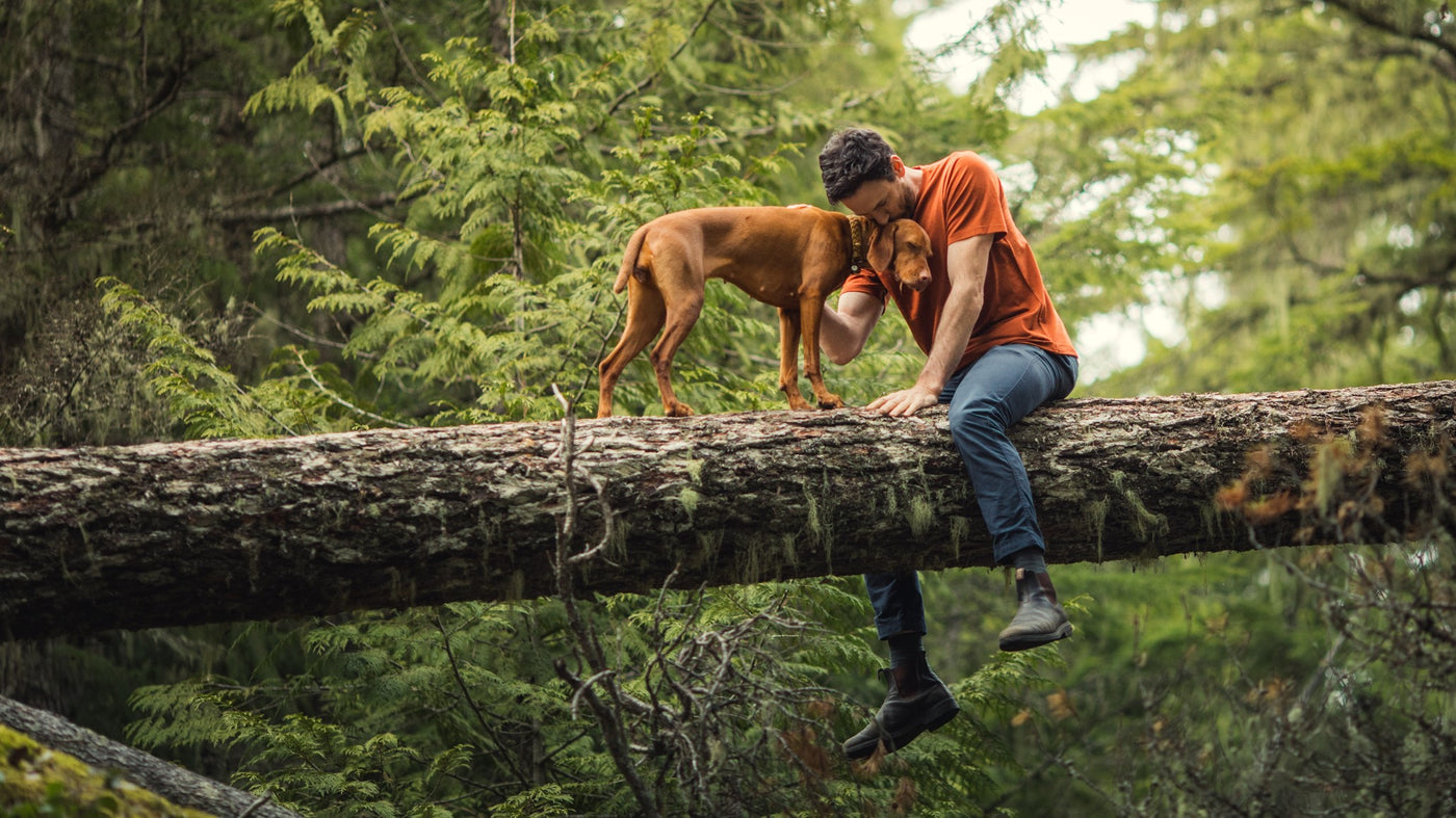 Model sitting on log with his dog