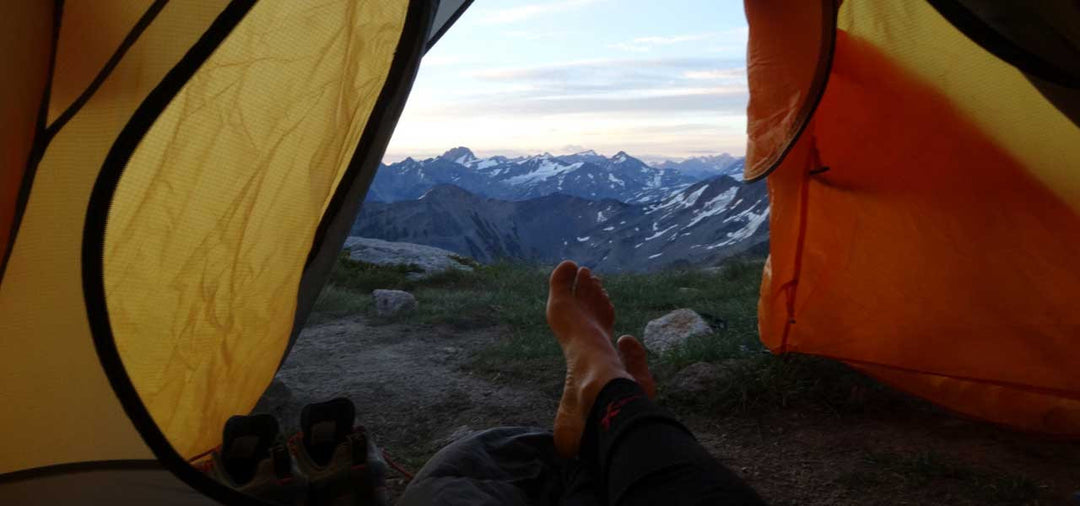 Feet being shown from a tent view over a mountain landscape