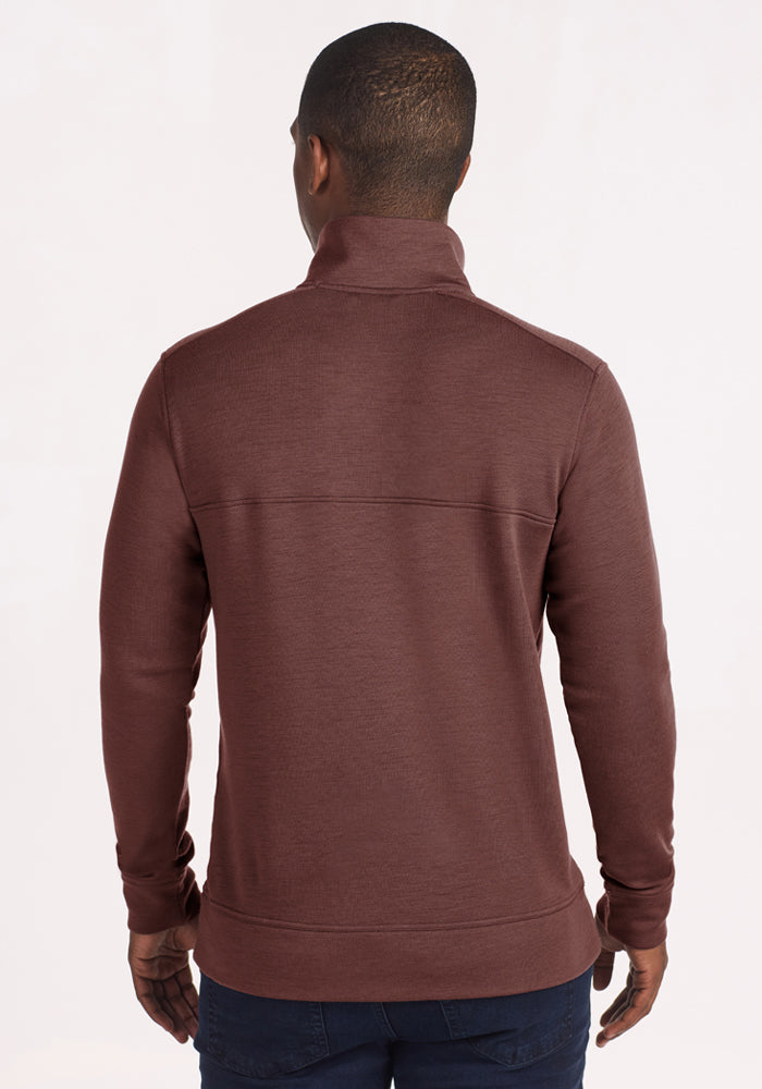 Man facing away in a Woolx Mason 1/4 Zip - Canyon Clay pullover and dark jeans, against a plain light background.