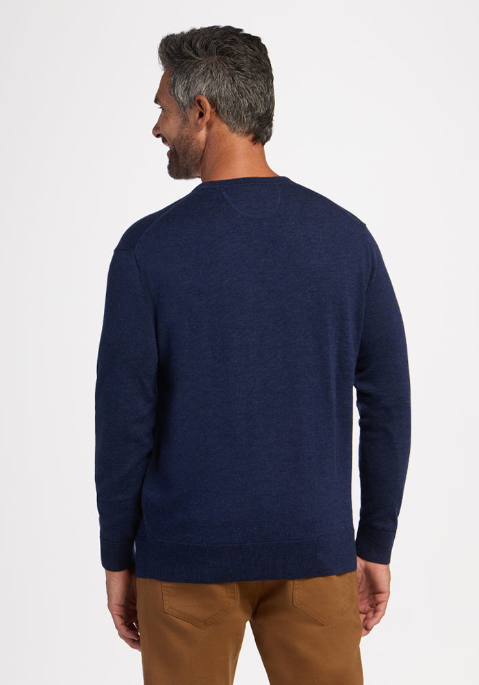 A man faces away in a Woolx Vincenzo Sweater - Ocean Cavern and brown pants, a true men’s staple on white background.