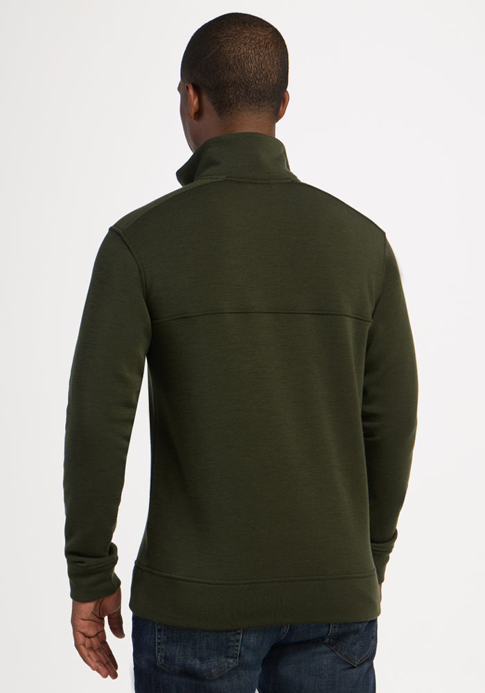 A person in a green Woolx Mason 1/4 Zip - Duffel Bag and jeans, shown from the back against a plain background.