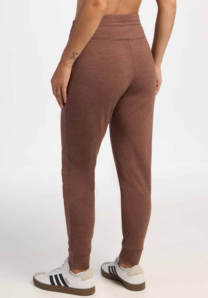 Person wears Woolx Willa Joggers in Sable Heather and white Adidas sneakers, shown from the back on plain background.