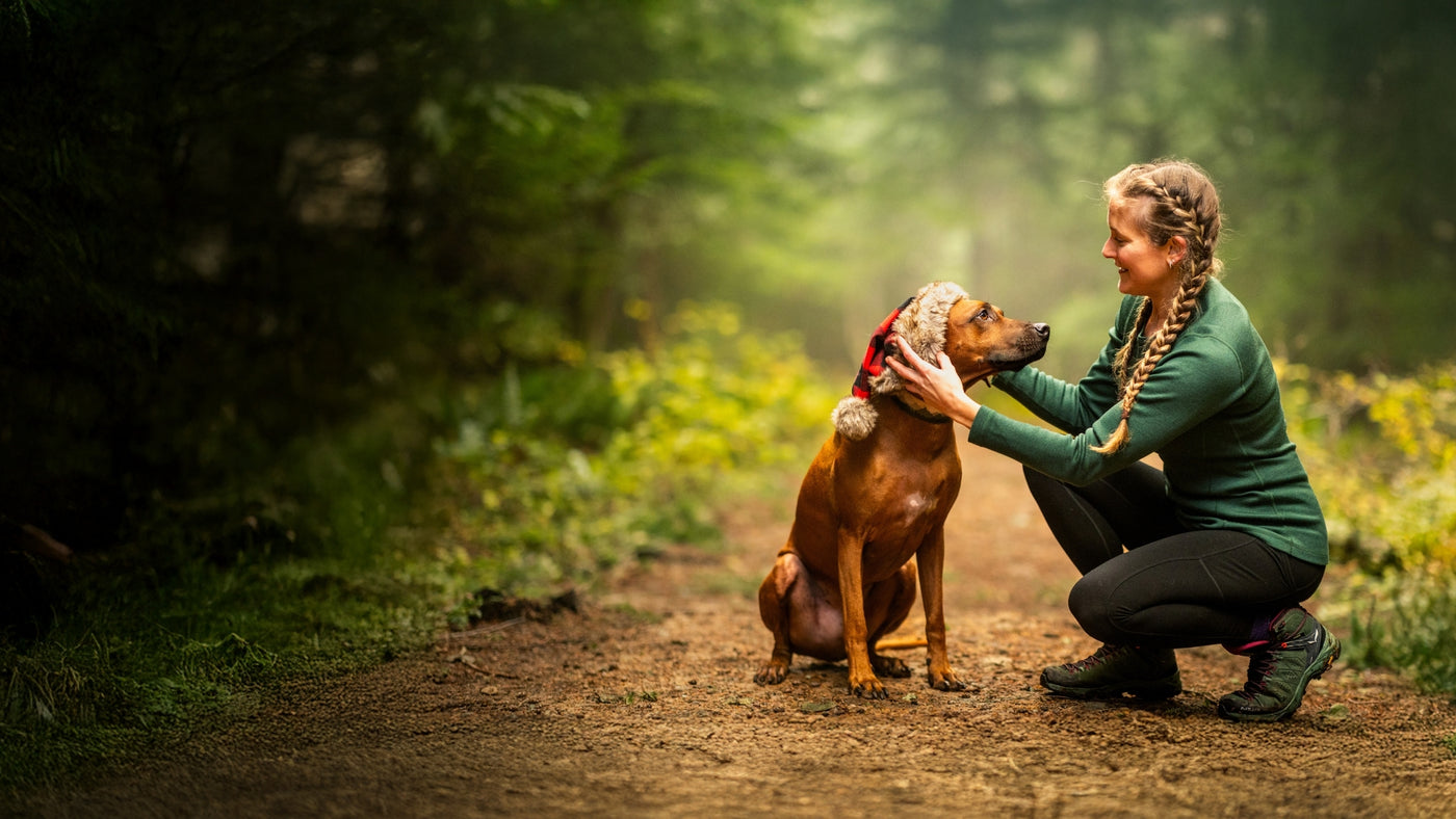 Model wearing Woolx on hiking path with her dog wearing santa hat