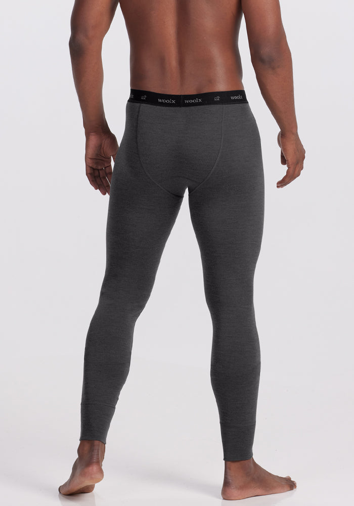 Man in Woolx Backcountry Leggings - Cinder Melange, barefoot, faces away from camera on white background.
