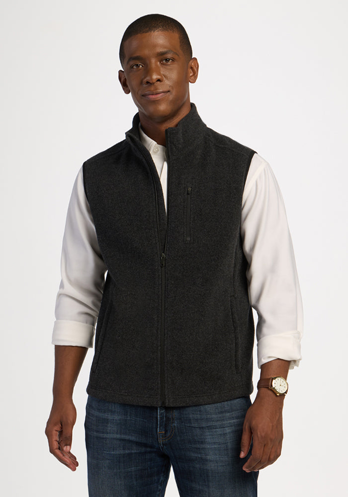 A man wearing a carbon black Woolx Everest Vest over a white button-down shirt. | Trell is 6’2”, wearing a size M