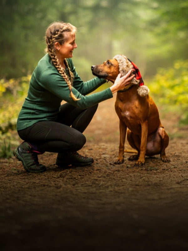 Model wearing Woolx on hiking path with her dog wearing santa hat mobile size