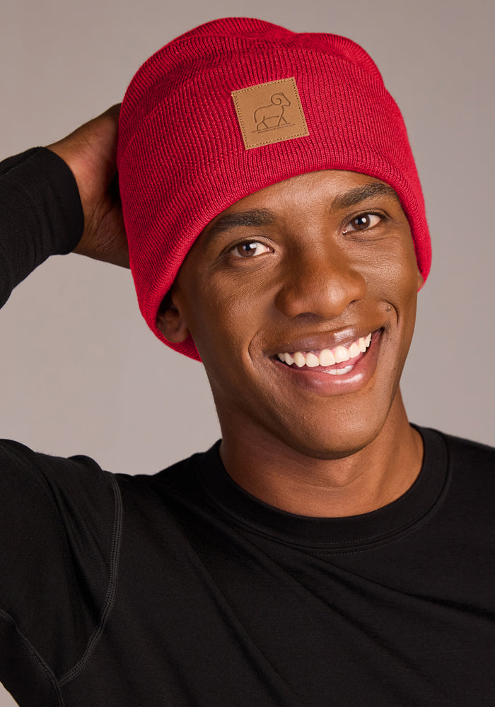 Smiling person in a Woolx Baylor Beanie - Maraschino Cherry and black shirt, hand touching back of head.