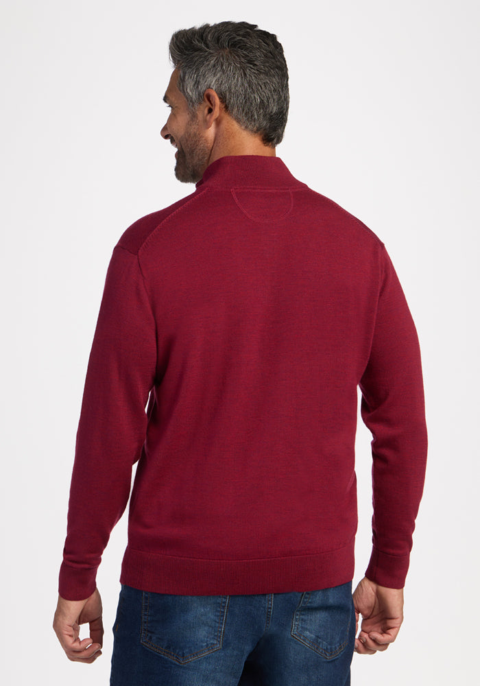 Man with short gray hair in a Woolx Enzo Quarter Zip - Beet Red sweater and blue jeans, facing away on white background.