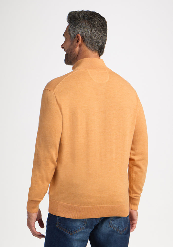 Man wears Woolx Enzo Quarter Zip in Butterscotch and blue jeans, facing away from the camera against a plain background.