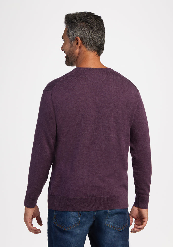 Man in Woolx Vincenzo Sweater - Purple Iris and blue jeans, facing away against a plain white background.