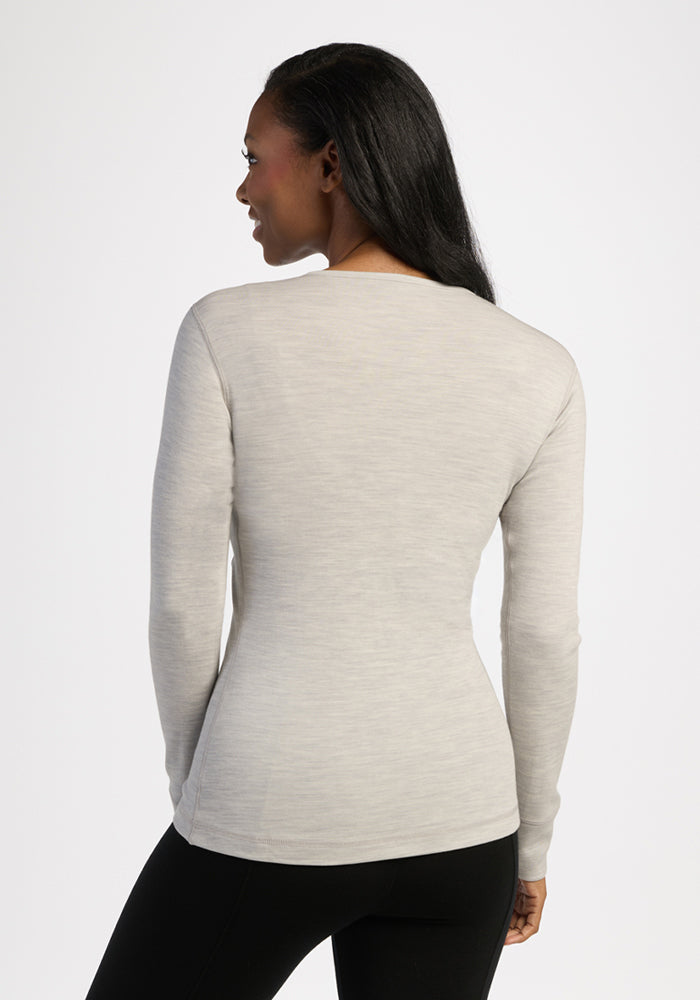 Woman in Woolx Hannah Long Sleeve Top - Light Ash and black pants, viewed from the back.