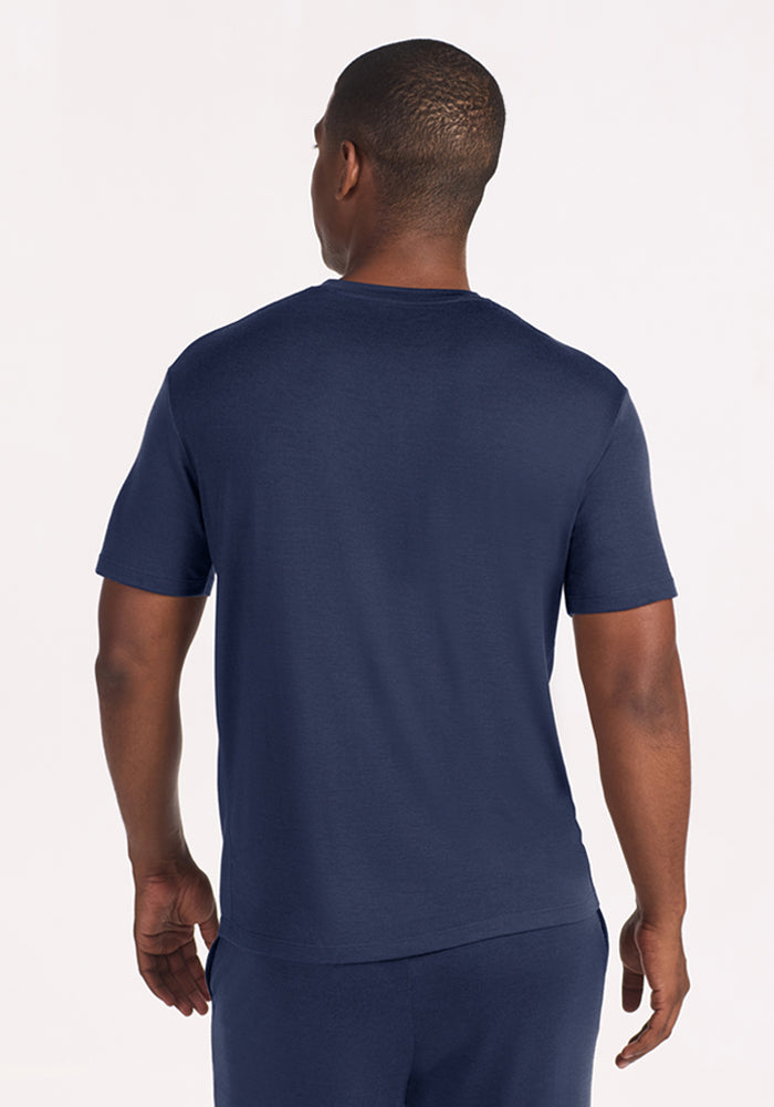 Back view of a person wearing a navy blue Woolx Finn Top - Deep Dive moisture-managing, short-sleeved crew neck shirt.