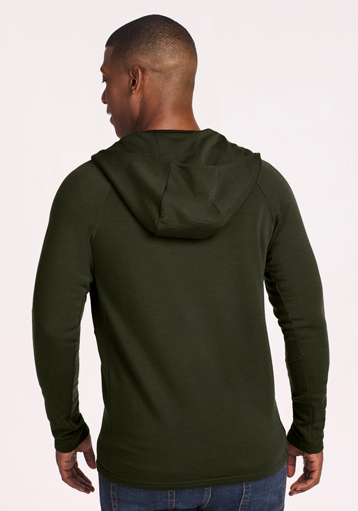Man facing away in Woolx Boulder Hoodie - Duffel Bag and blue jeans, standing against a light background.