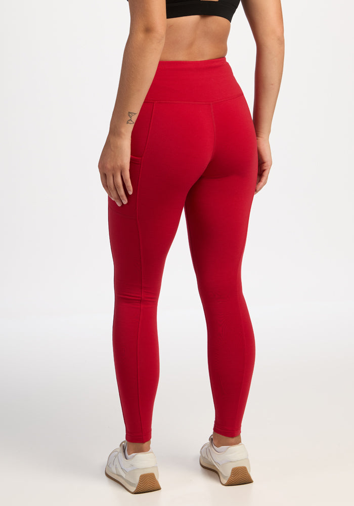 Person in a black sports bra and Woolx Piper Pocket Leggings - Maraschino Cherry, with moisture-wicking comfort.