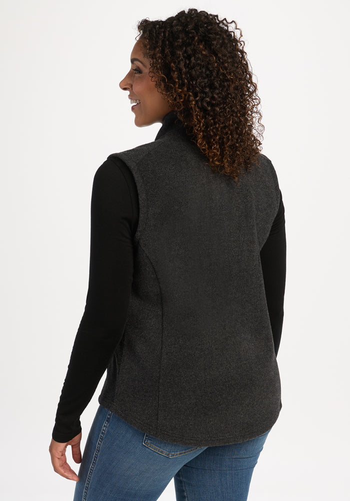 Woman with curly hair smiles in the Woolx Haley Vest - Carbon Black, black shirt, and jeans, facing away.