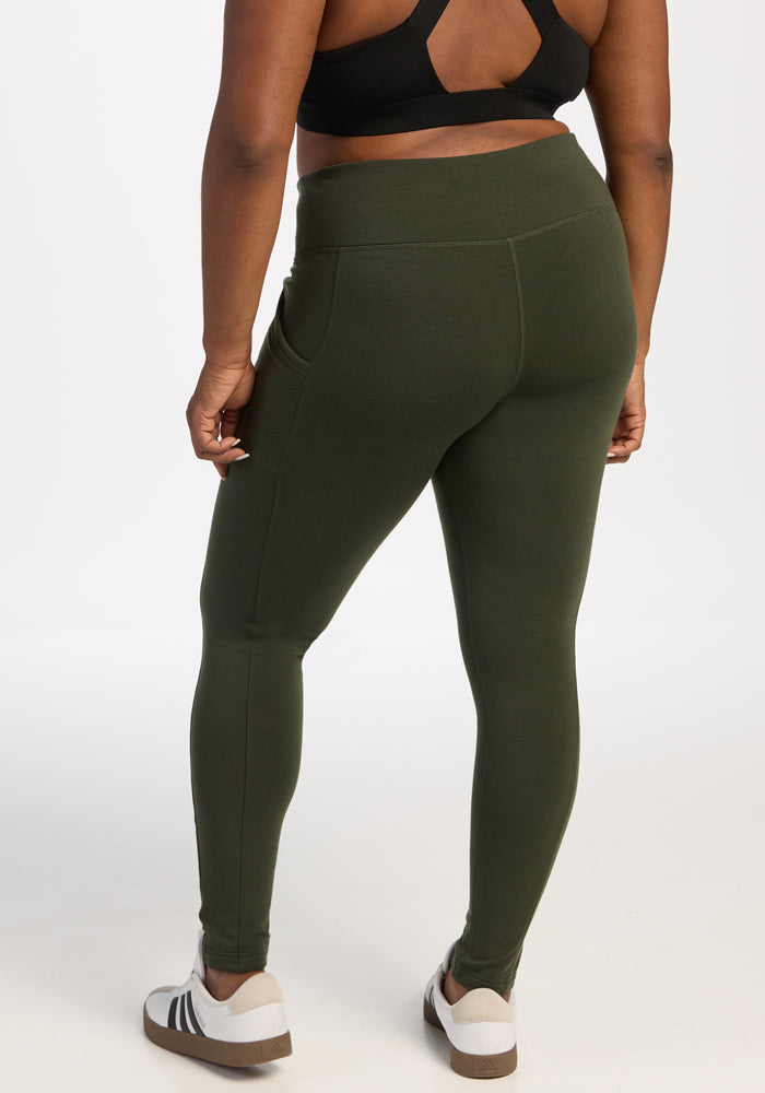 Model with a Woolx Piper Pocket Tall Duffel Bag, facing away, in leggings, sports bra, and white sneakers.