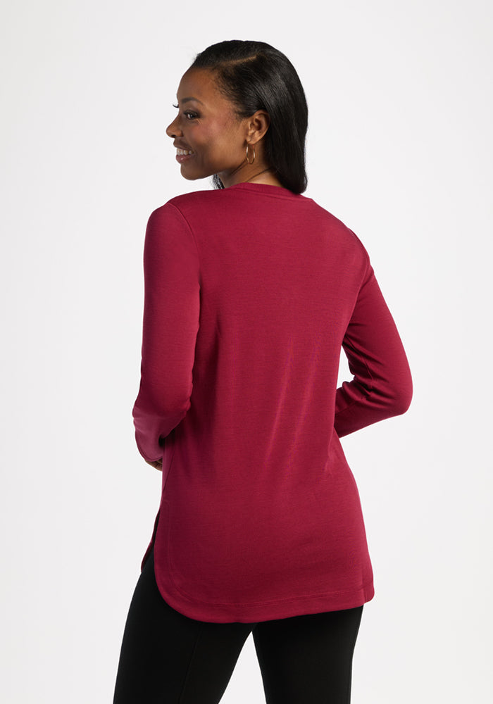 Woman in a Woolx Blair Petite Tunic - Beet Red and black pants, standing and smiling, facing away from the camera.