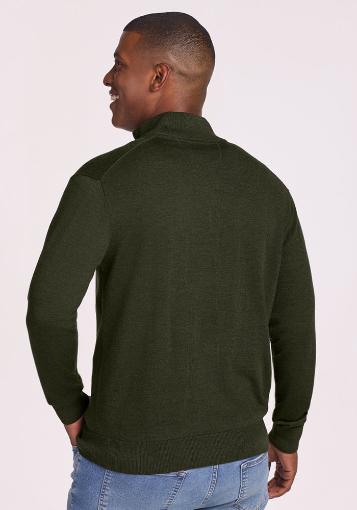 Man wearing a Woolx Enzo Quarter Zip - Duffel Bag sweater and blue jeans, standing with his back turned and smiling.