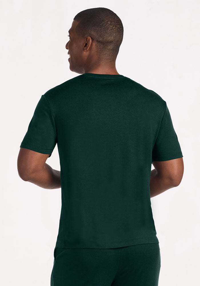 A man viewed from behind, wearing a deep pine Woolx Finn Top, a dark green Merino wool moisture-managing lounge shirt.