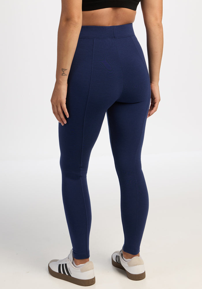 Woman in Woolx Stella Tall - Ocean Cavern leggings, midriff down, back to camera, paired with sneakers.