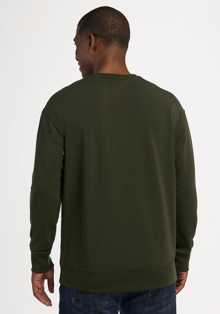 Back view of a person wearing a moisture-wicking, dark olive green Woolx Miles Crewneck - Duffel Bag merino sweater.