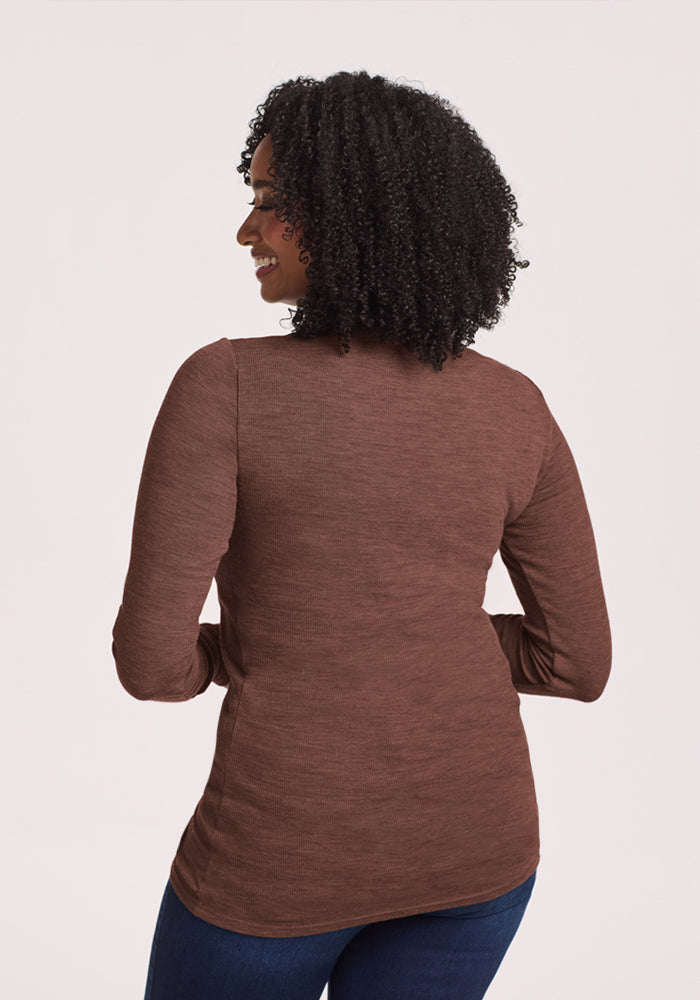 Woman with curly hair faces away, wearing Woolx Sage Ribbed Turtleneck in Sable Heather and dark blue jeans.