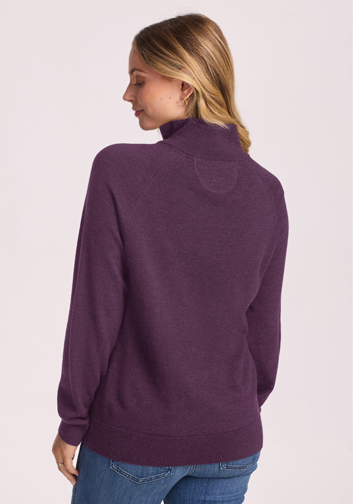 Woman with blond hair in the Woolx Collins Half Zip Sweater - Purple Iris and blue jeans, facing away.