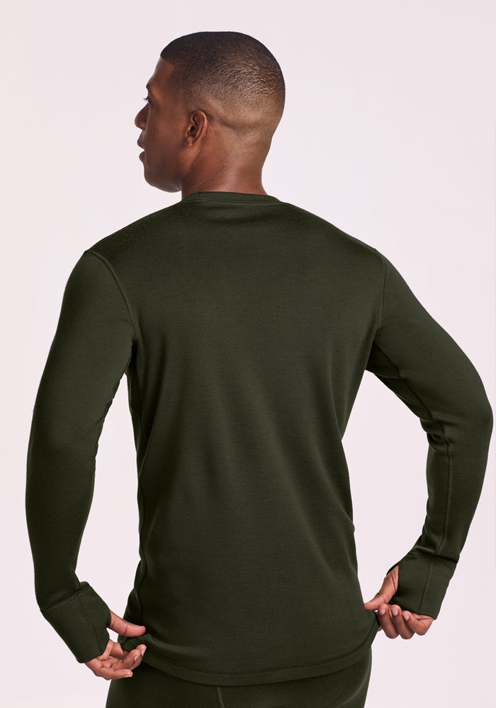 Man wears the Woolx Glacier Long Sleeve Crew - Duffel Bag, back to camera, hands on hips, facing left.
