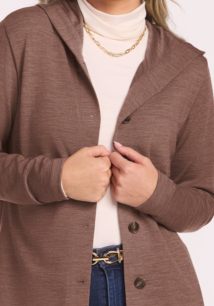 Woman in the Woolx Edna Hooded Cardigan - Sable Heather over a cream turtleneck, gold chain, and blue jeans.