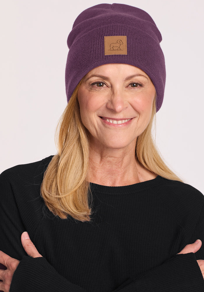 Woman in Woolx Baylor Beanie - Purple Iris and black sweater, arms crossed, against a plain background.