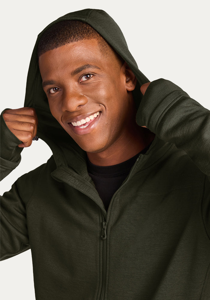 Smiling man wearing a forest green, moisture-wicking Merino wool Grizzly Sweatshirt - Duffel Bag zip-up hoodie with hood up.