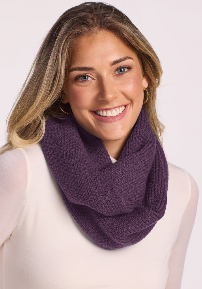 Smiling woman in a white top wears the Woolx Noelle Infinity Scarf - Purple Iris against a light background.