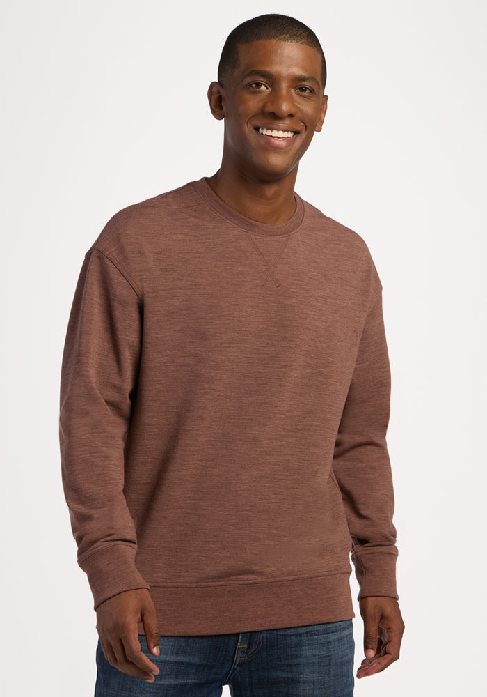 A smiling man wearing a brown, temperature-regulating Woolx Miles Crewneck - Sable Heather sweatshirt. 