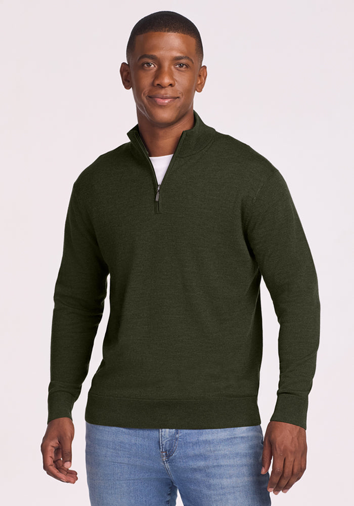 Man in Woolx Enzo Quarter Zip - Duffel Bag and light blue jeans, standing and smiling against a plain background.