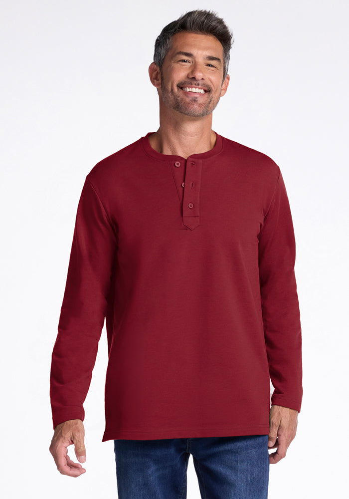 Smiling man in Woolx Jackson Henley - Pinot Noir and blue jeans stands against a plain white background. 