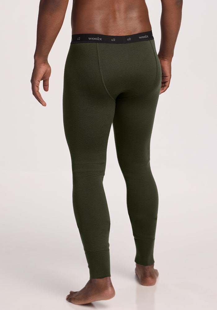 A man stands barefoot, wearing Woolx Arctic Leggings—ultra-heavyweight Merino base layer in Duffel Bag green.