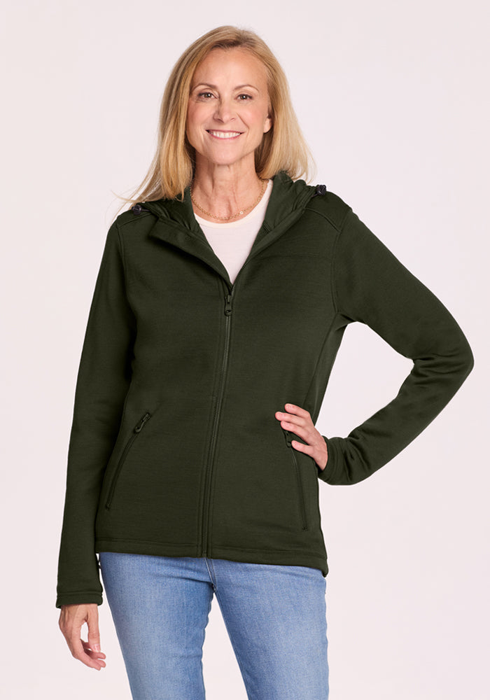 Woman in a Woolx Cubby Hooded Sweatshirt - Duffel Bag and blue jeans, standing and smiling against a plain background. 