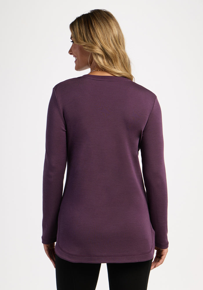 Woman with long blonde hair wears the Woolx Blair Tunic in Purple Iris, shown from the back on a plain background.