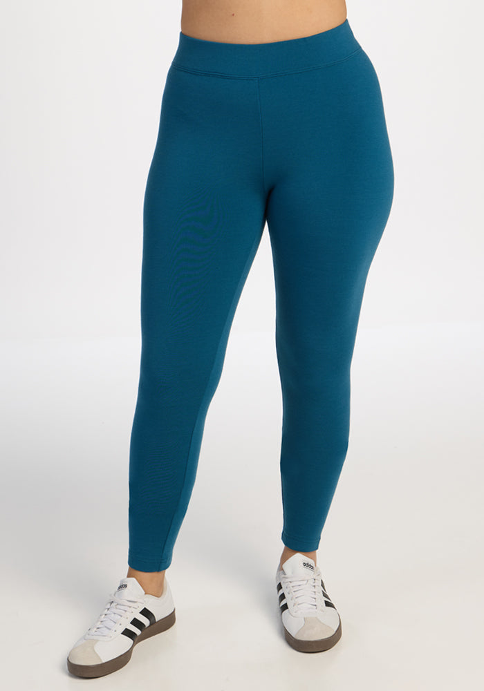 Person in Woolx Stella Leggings - Blue Pine and white sneakers with black stripes, standing on a white background. 