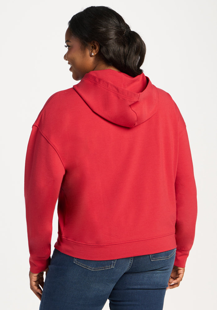 Woman in Woolx Lizzy Hoodie - Maraschino Cherry and blue jeans, smiling, shown from the back, looking left.