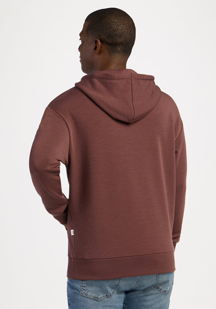 Man in Woolx Watson Pullover - Canyon Clay, facing away, pairs with jeans against a plain backdrop.