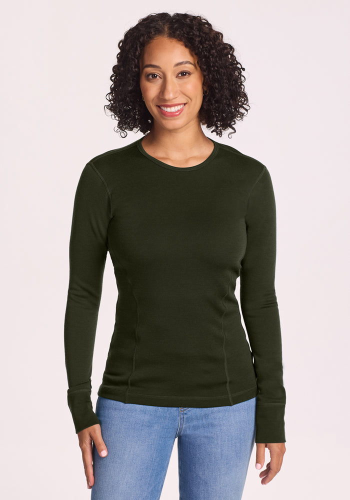 Woman in Woolx Hannah Long Sleeve Top - Duffel Bag and jeans, smiling against a light neutral background. 
