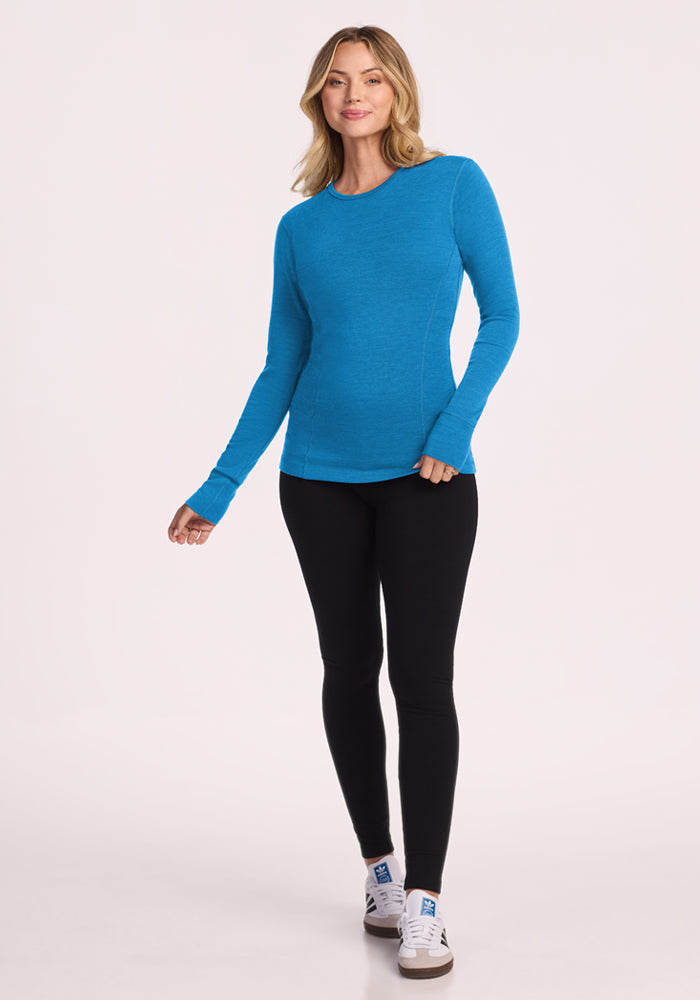 Woman in Woolx Hannah Long Sleeve Top - Blue Razz and black leggings, smiling against a plain background.