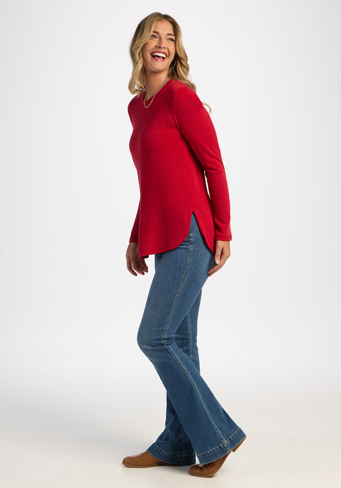 Woman in the Woolx Blair Tunic - Maraschino Cherry smiles, enjoying lightweight warmth against a white background.