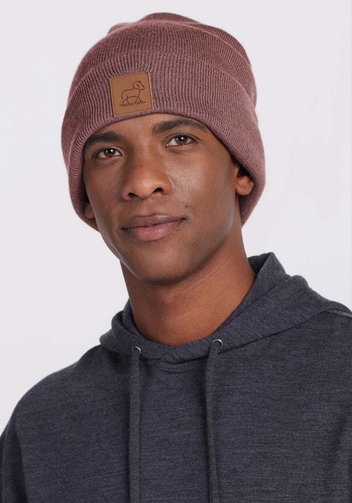 Man wears Woolx Baylor Beanie in Sable Heather and a dark hoodie, facing camera with a neutral look on plain backdrop.