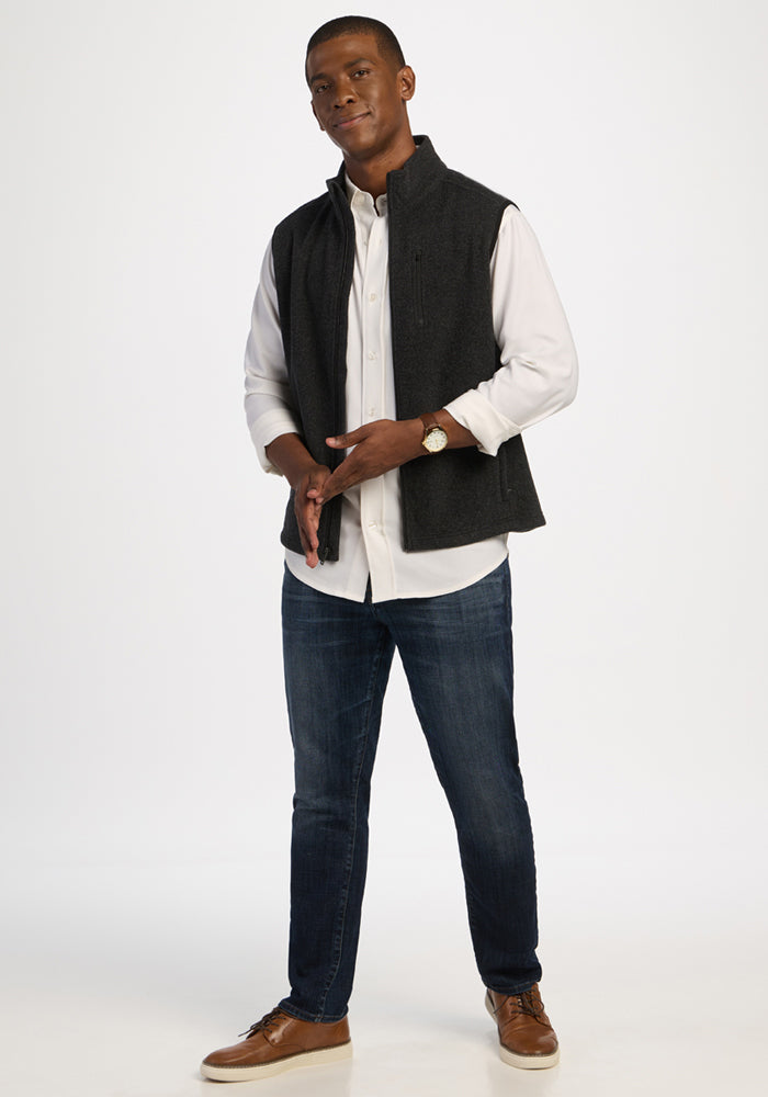 Man wearing a Carbon Black Everest Vest over a white button-down shirt and blue jeans.
