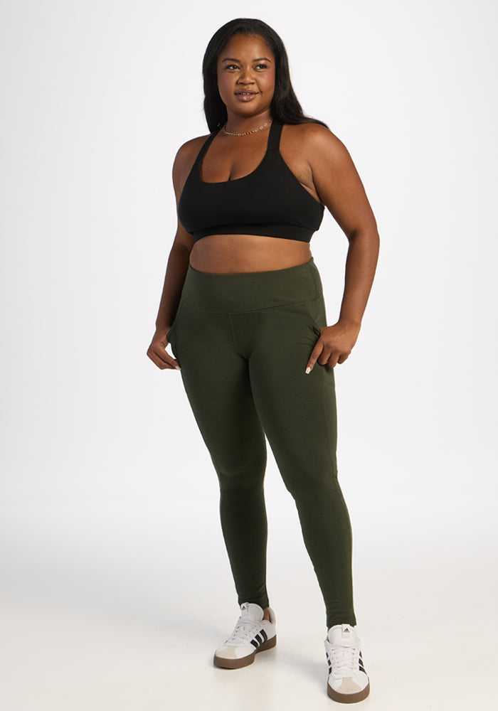 Woman in Woolx Piper Pocket Leggings - Duffel Bag and black sports bra poses confidently against a white backdrop.