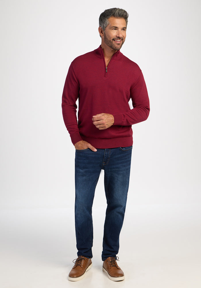 Man in a Woolx Enzo Quarter Zip - Beet Red, blue jeans, and brown shoes stands smiling against white.