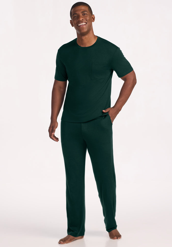 A smiling man wearing a moisture-managing Finn Top - Deep Pine shirt and matching pants.