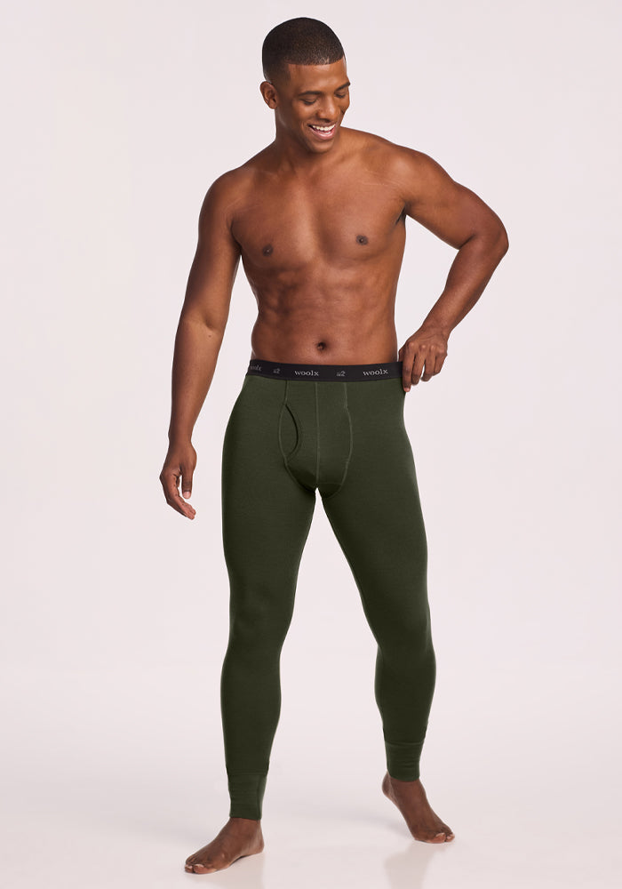 Smiling man poses in Woolx Backcountry Leggings - Duffel Bag with black waistband on a light background.